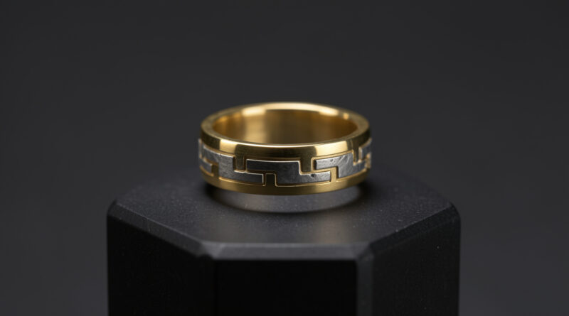 Bague contemporaine en fer météoritique sertie d’or jaune, ornée de motifs géométriques discrets, présentée sur un fond sombre de musée avec une lumière douce.